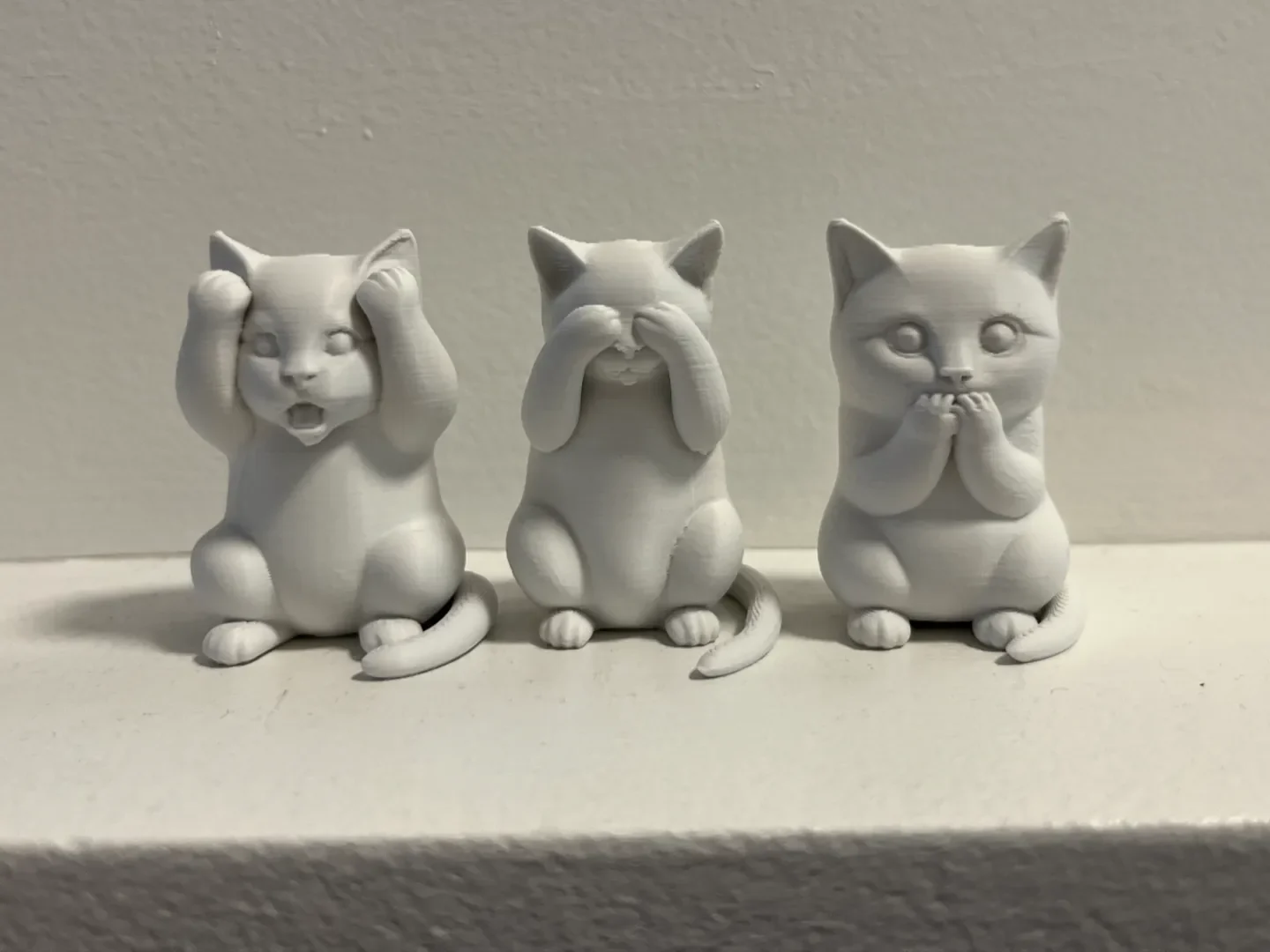 Three small grey kitten figurines covering their eyes, ears and mouth