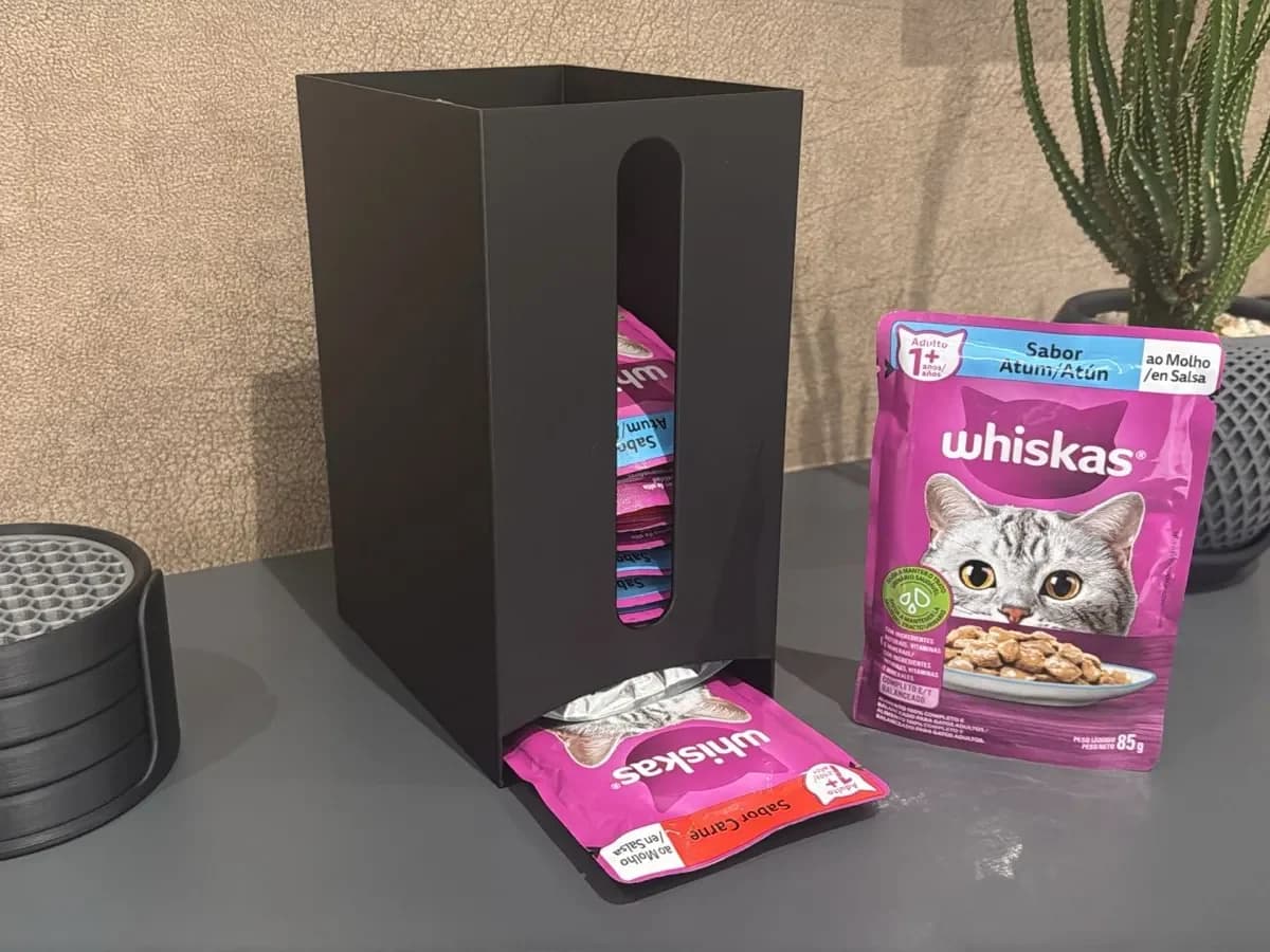 Black cat food pouch dispenser next to pouches of cat food